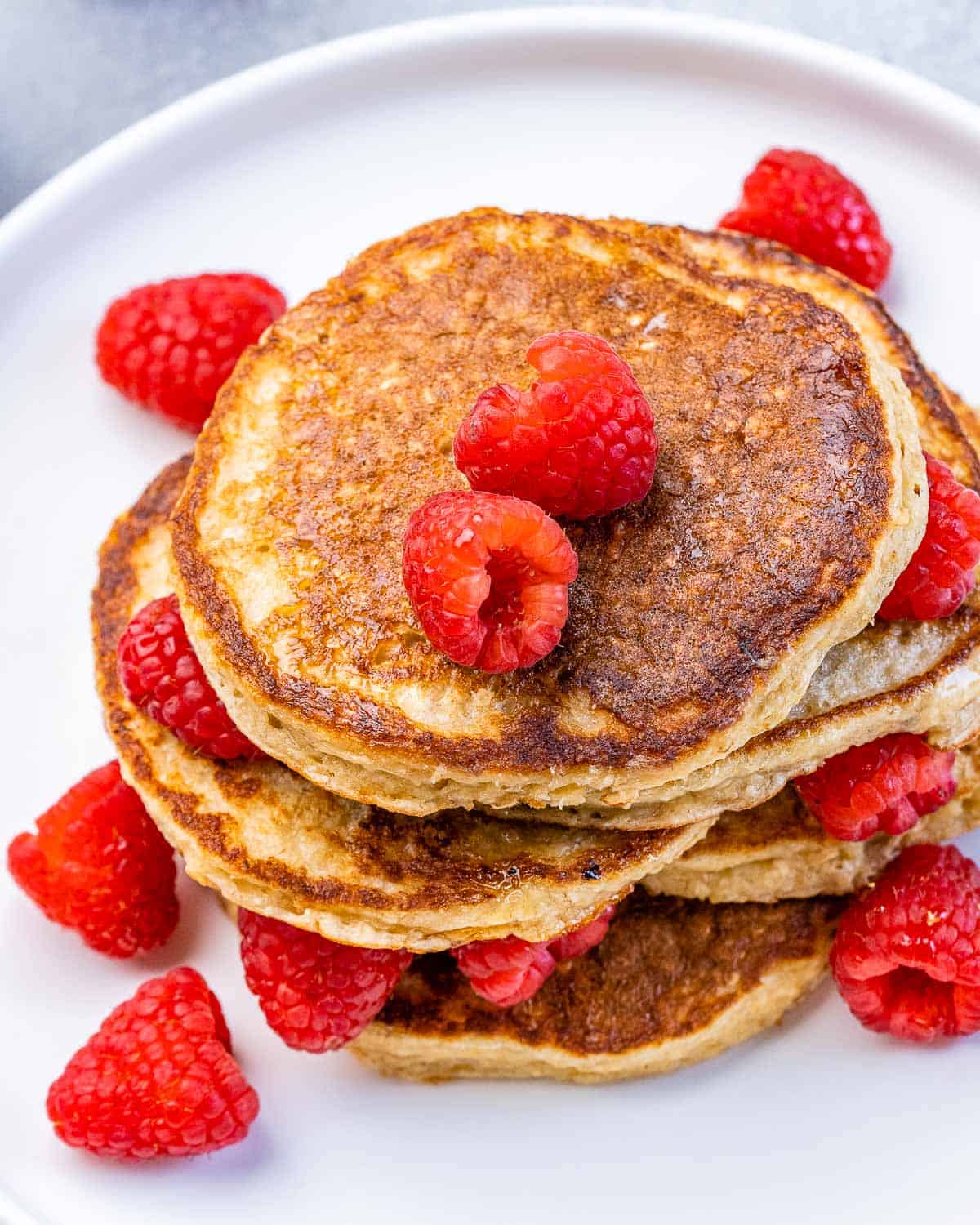 Cottage cheese pancakes served in a stack with fresh raspberries.
