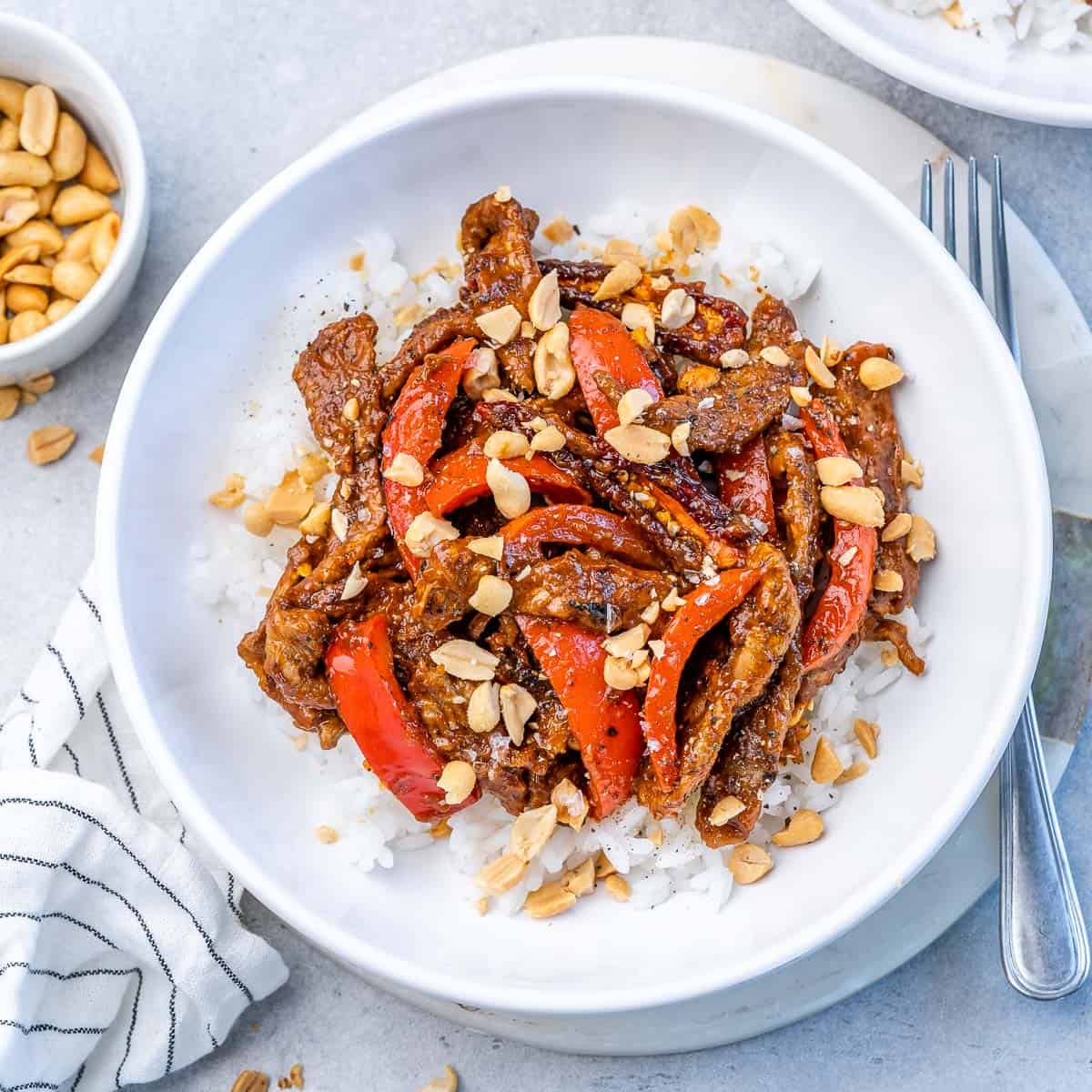 top view white bowl with rice and sauteed kung pao beef with red bell pepper