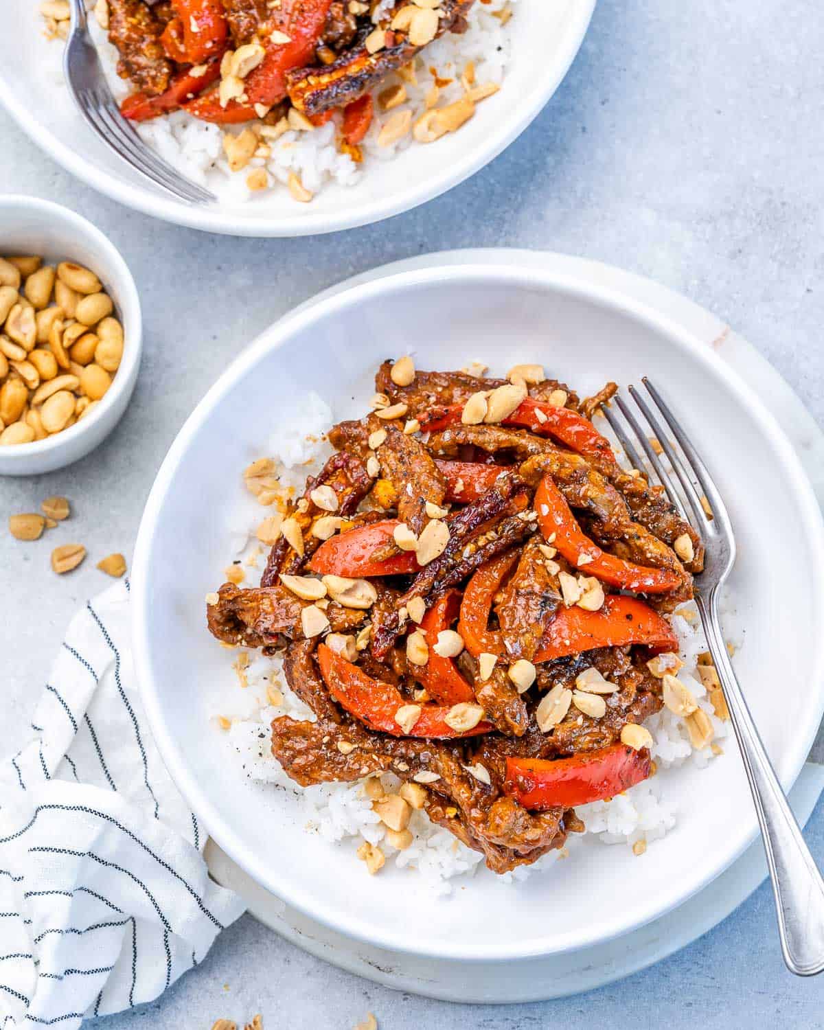 Kung pao beef served over rice in a white bowl.