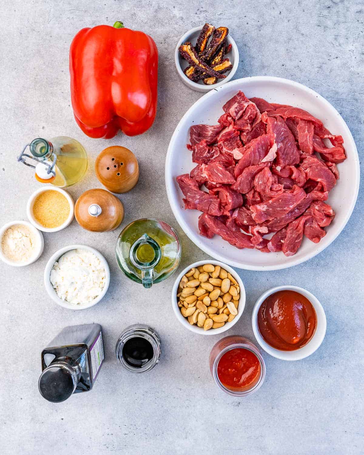 Ingredients like beef, sauce, oil, seasonings and peanuts divided into small bowls.