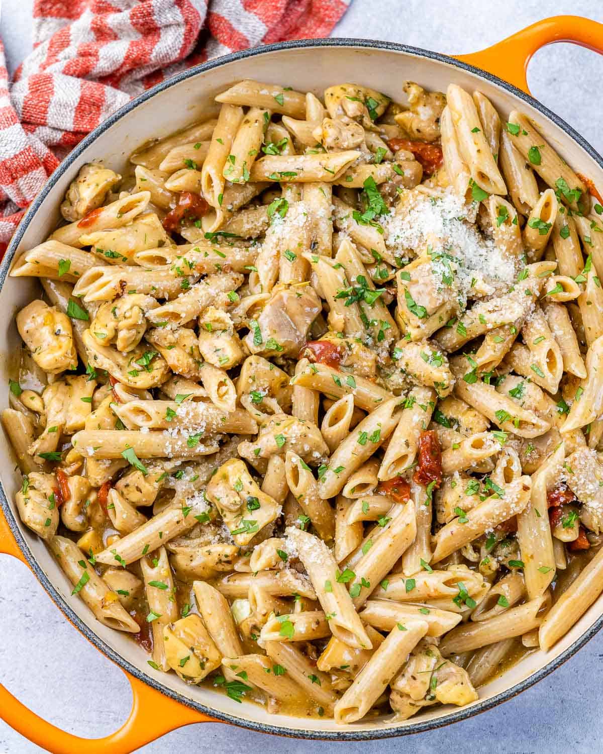 top view of chicken and penne pasta that's creamy in an orange skillet