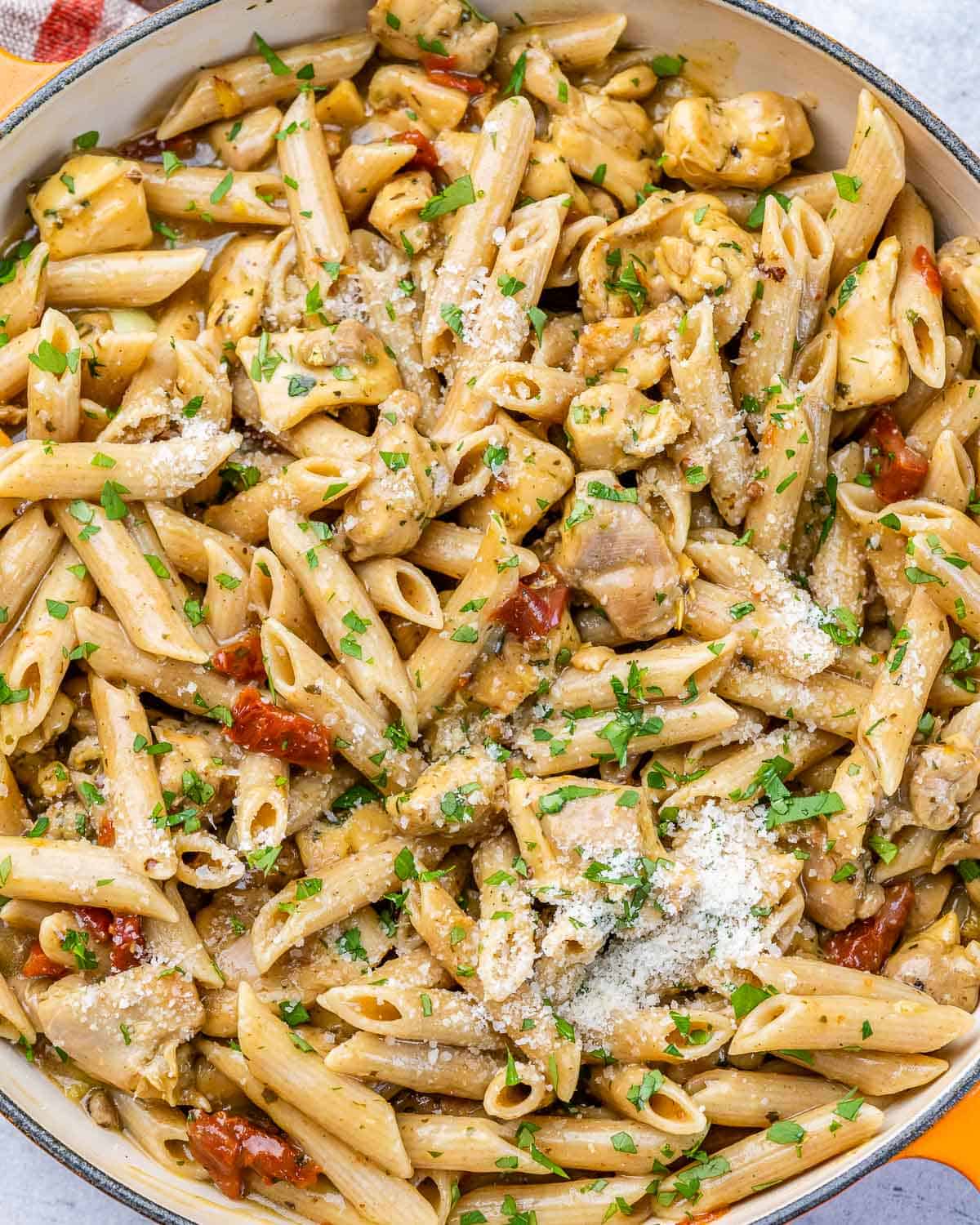 top view of creamy chicken pasta in a pan garnished with parmesan cheese