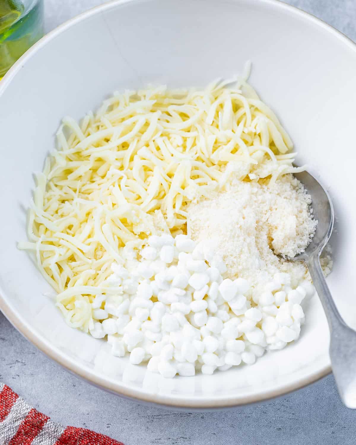 Mixing cottage cheese with mozzarella and parmesan cheese in a large bowl.