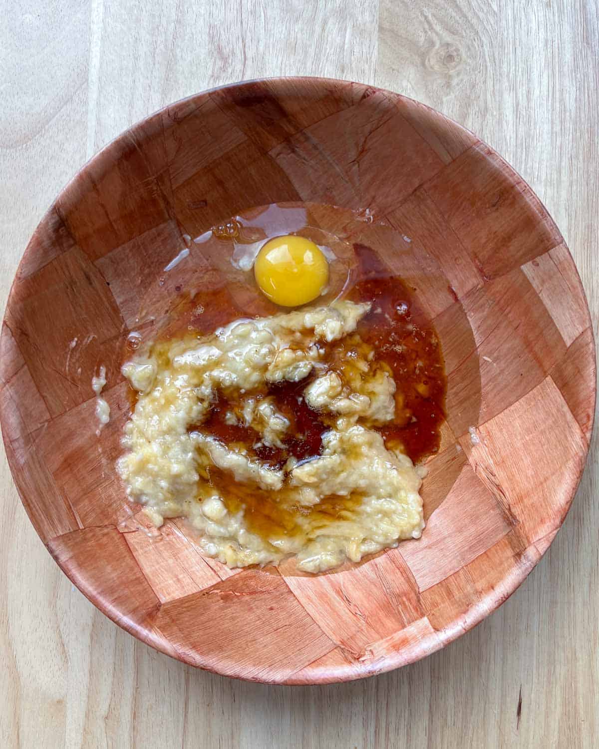 mashed banana, eggs oil, and vanilla added to a bowl.