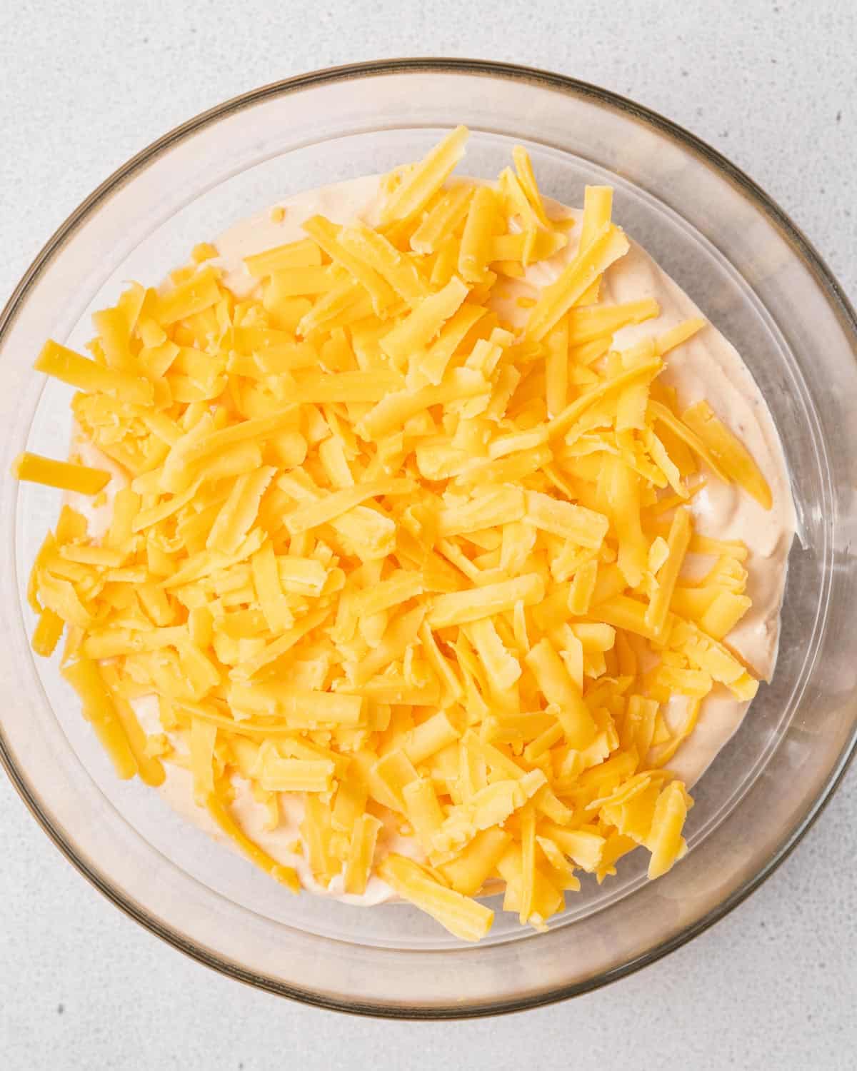 Shredded cheese on top of blended cottage cheese in a bowl.