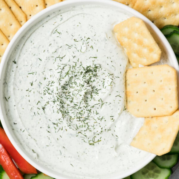 creamy ranch dip in a bowl with crackers in dip and fresh dish garnish