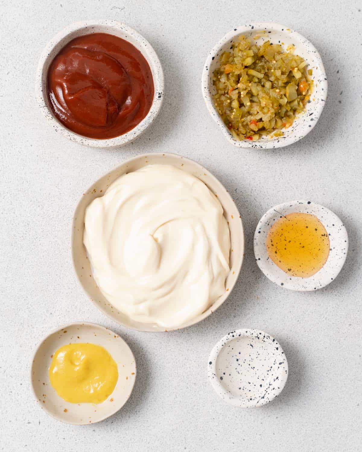 Bowls filled with mayo, ketchup, mustard and vinegar.