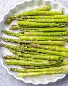 coated and seasoned asparagus in a dish.