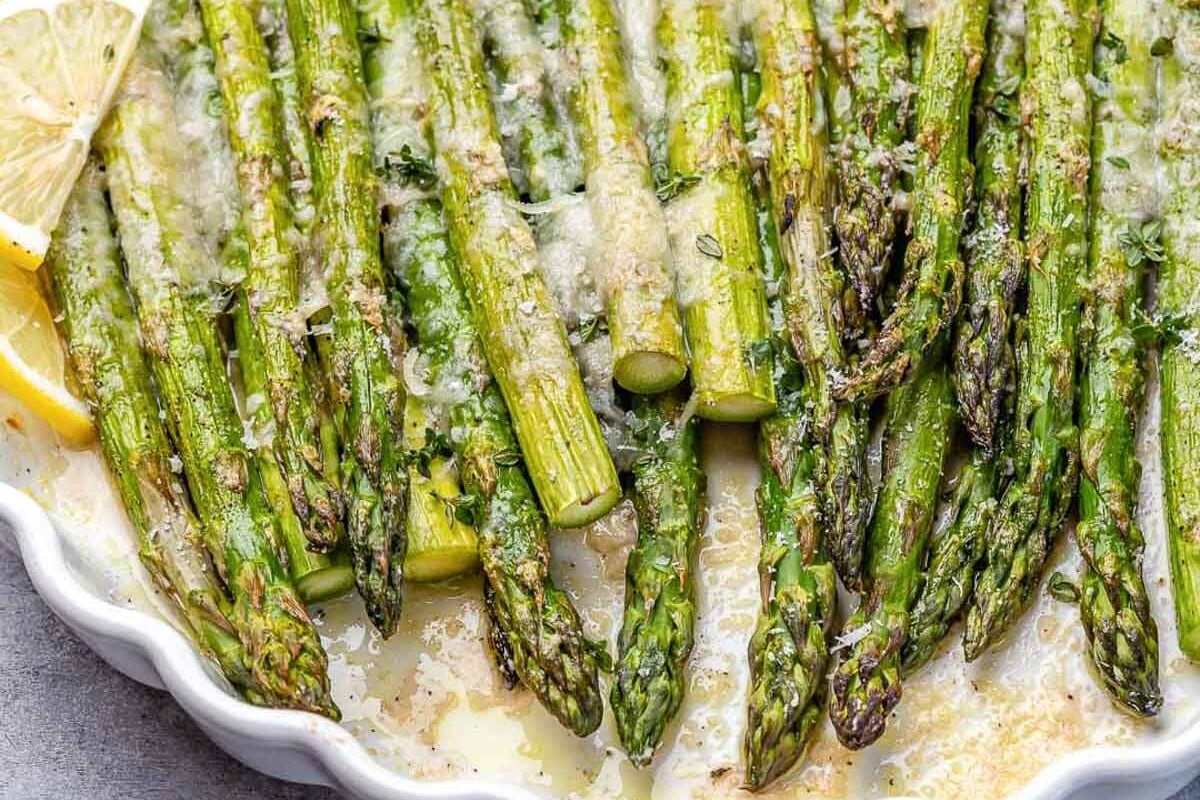 baked asparagus with parmesan cheese and lemon garnish.