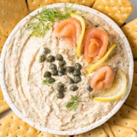 top view of creamy smoked salmon dip garnished with fresh smoked salmon, lemon slices, capers, and fresh dill