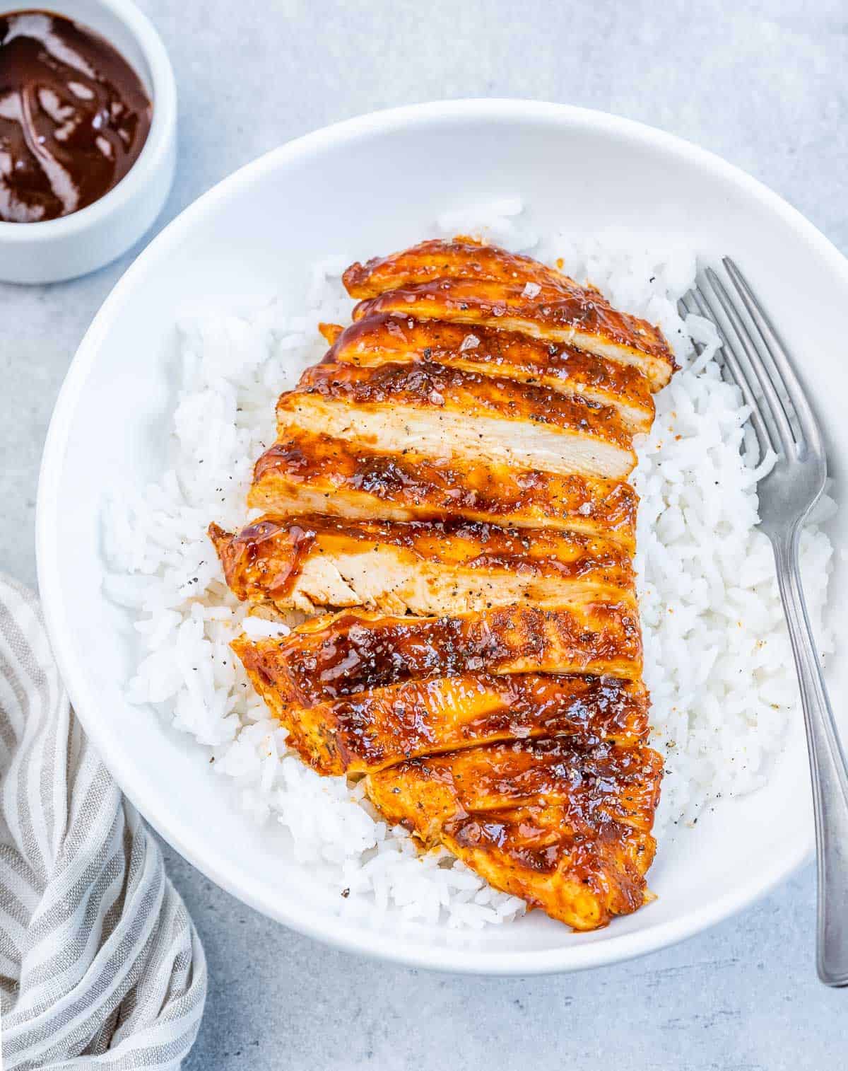 Sliced air fryer bbq chicken over rice in a white bowl.