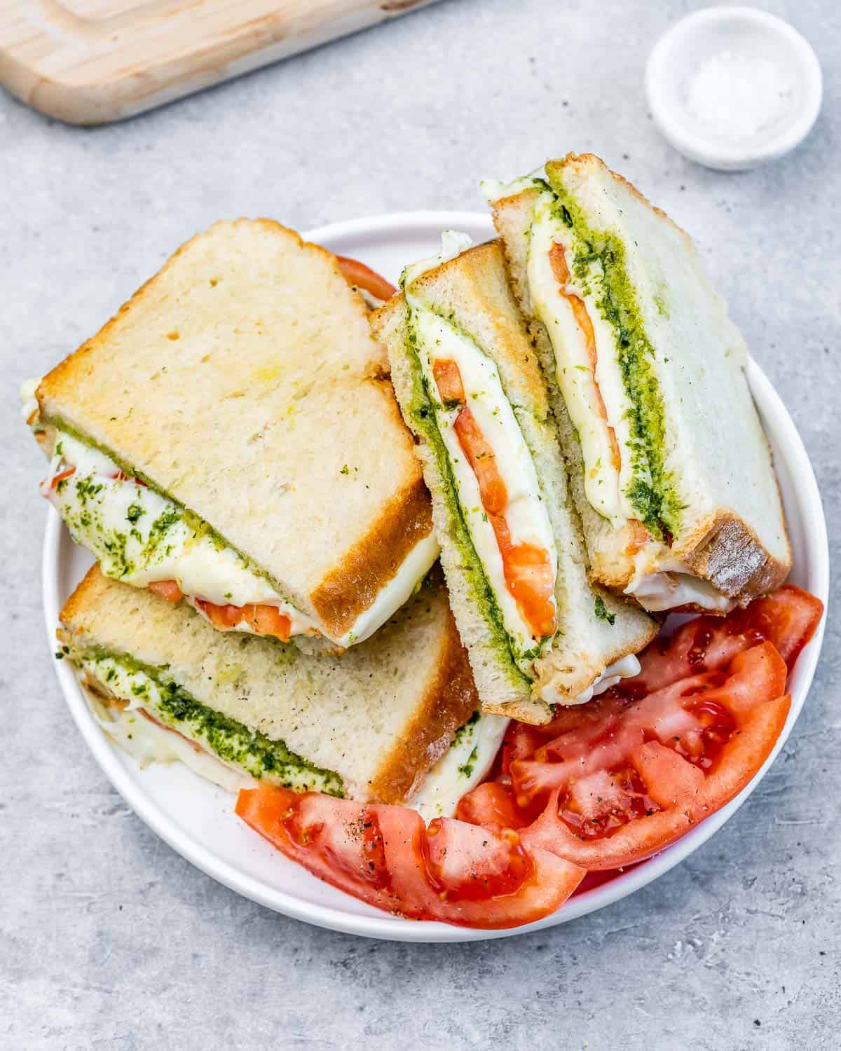 Air fryer grilled cheese sandwich on a white plate with tomato slices.