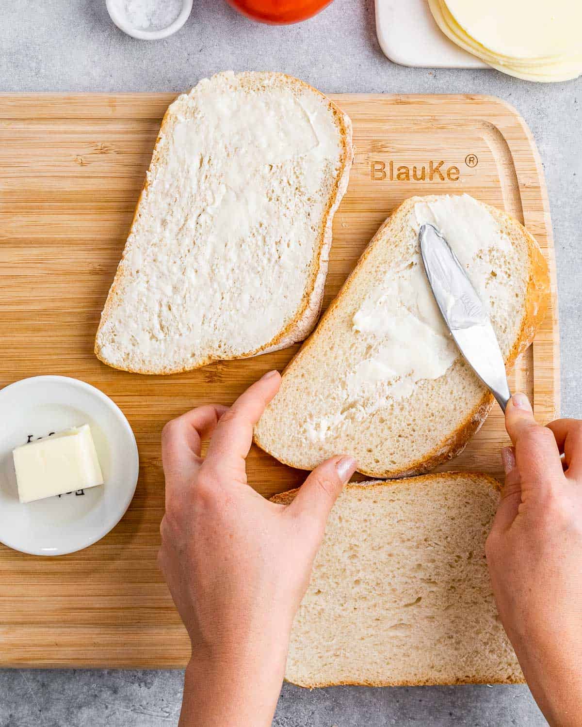 Spreading butter on top of bread slices.