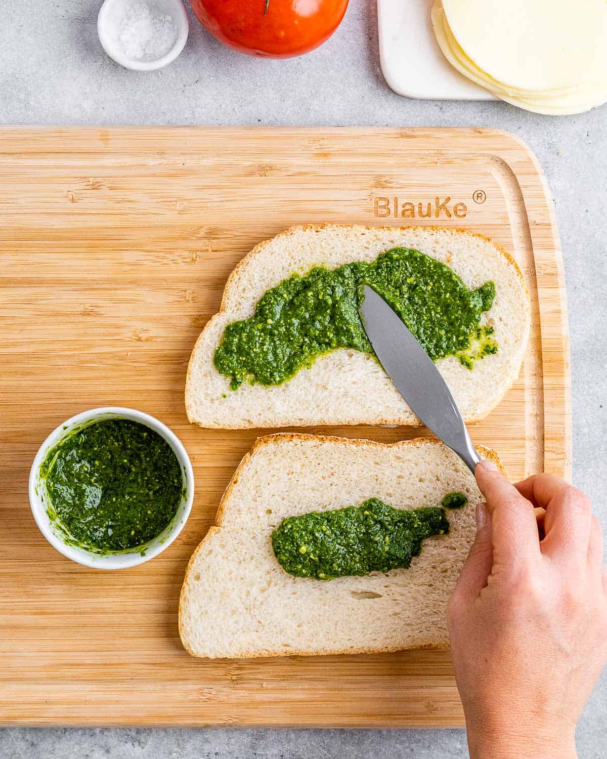 Spreading pesto over sliced bread.