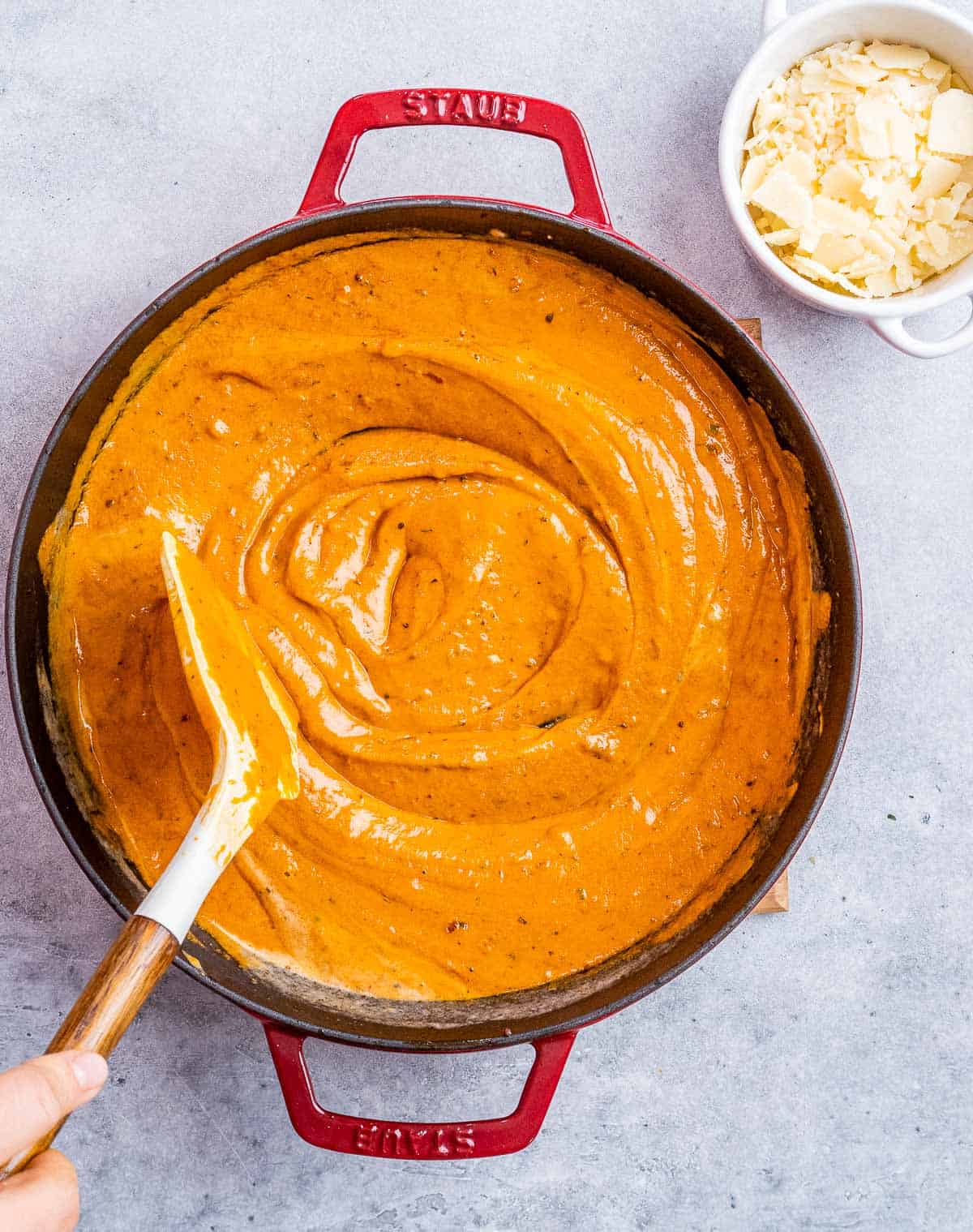 Stirring together cream pasta sauce in a large skillet.