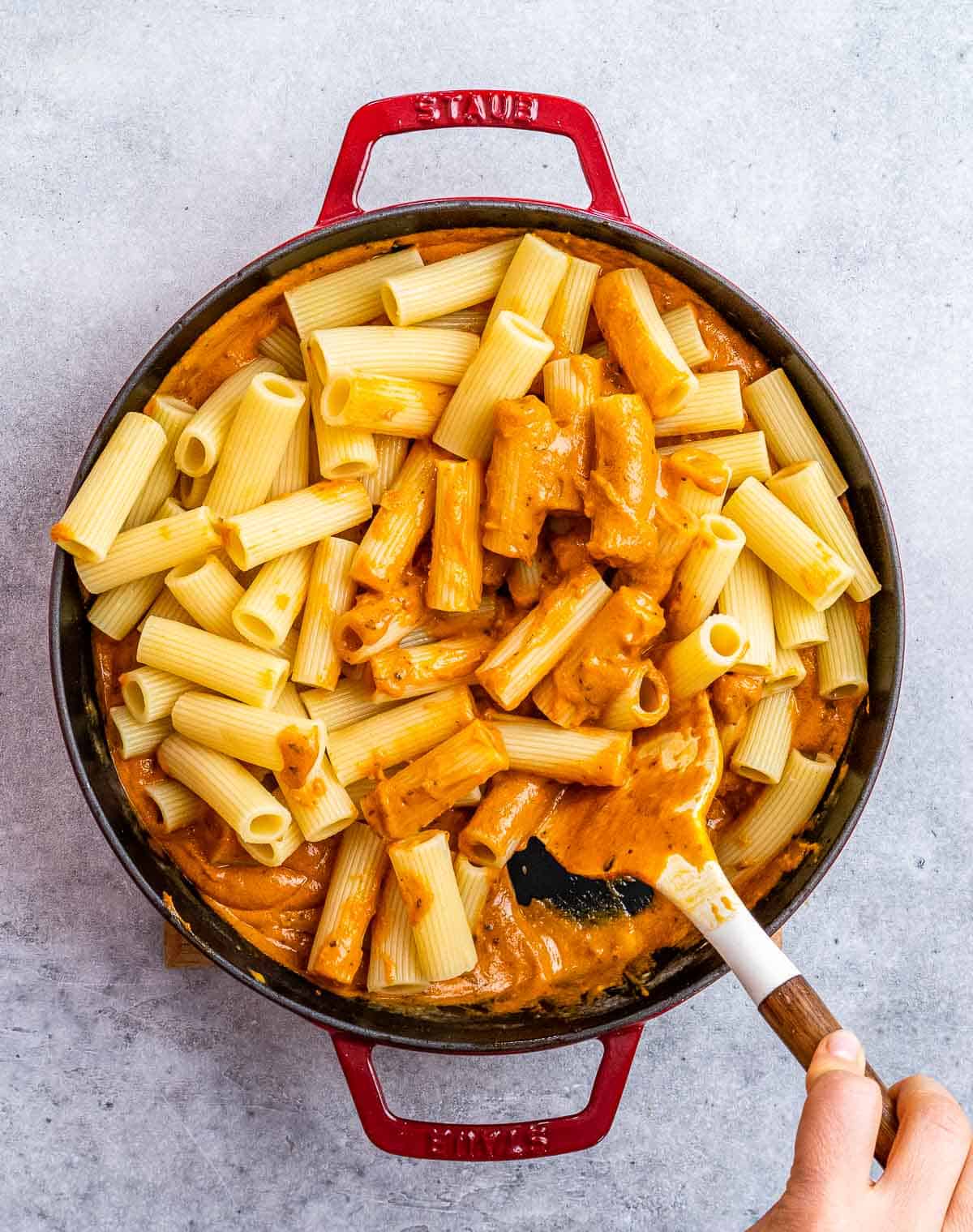 Stirring pasta in a creamy pasta sauce.