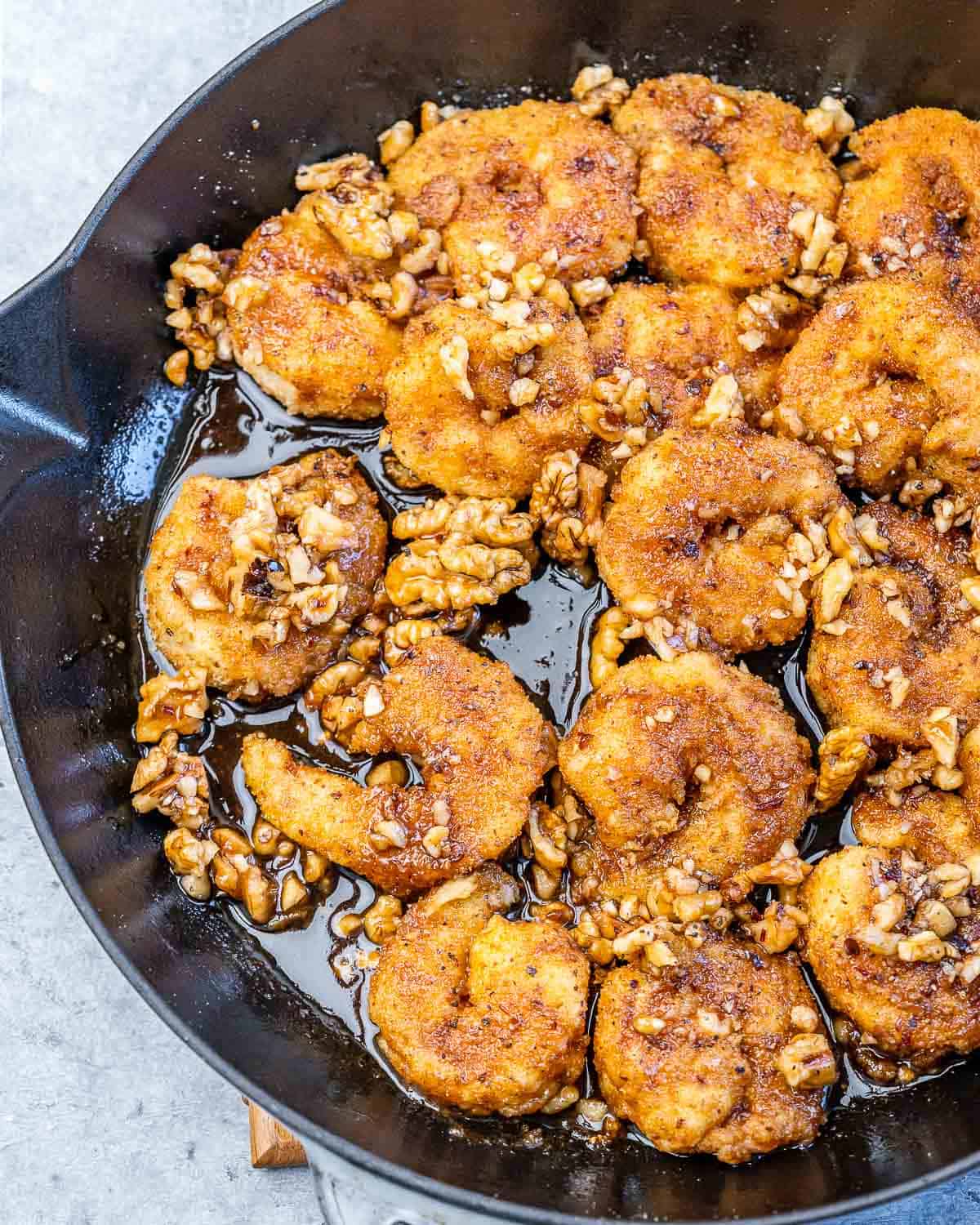 Honey walnut shrimp cooking in an iron skillet.