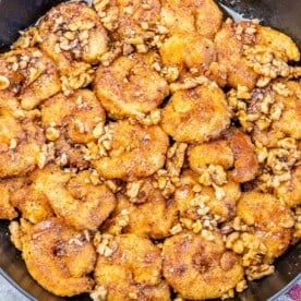 a black skillet with cooked honey walnut shrimp.