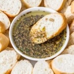a slice of bread dipped in a bowl of olive oil bread dip.