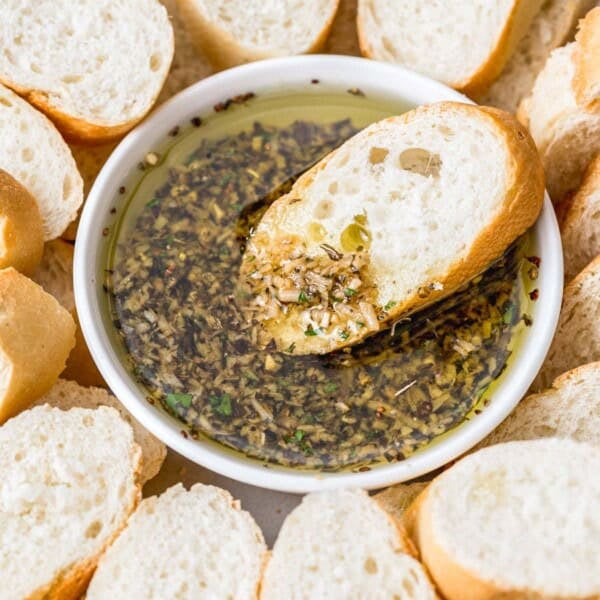 a slice of bread dipped in a bowl of olive oil bread dip.