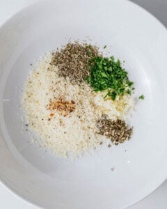 ingredients for olive oil bread dip added to a bowl.