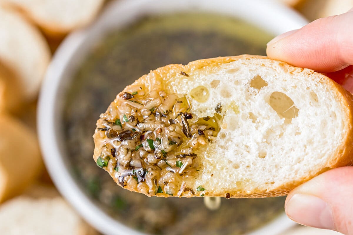 hand holding bread dipped in olive oil herb dip.