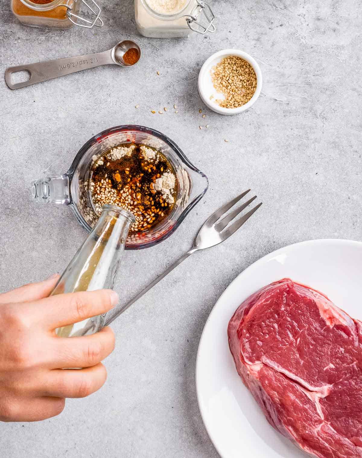 Mixing together marinade in a glass measuring cup.