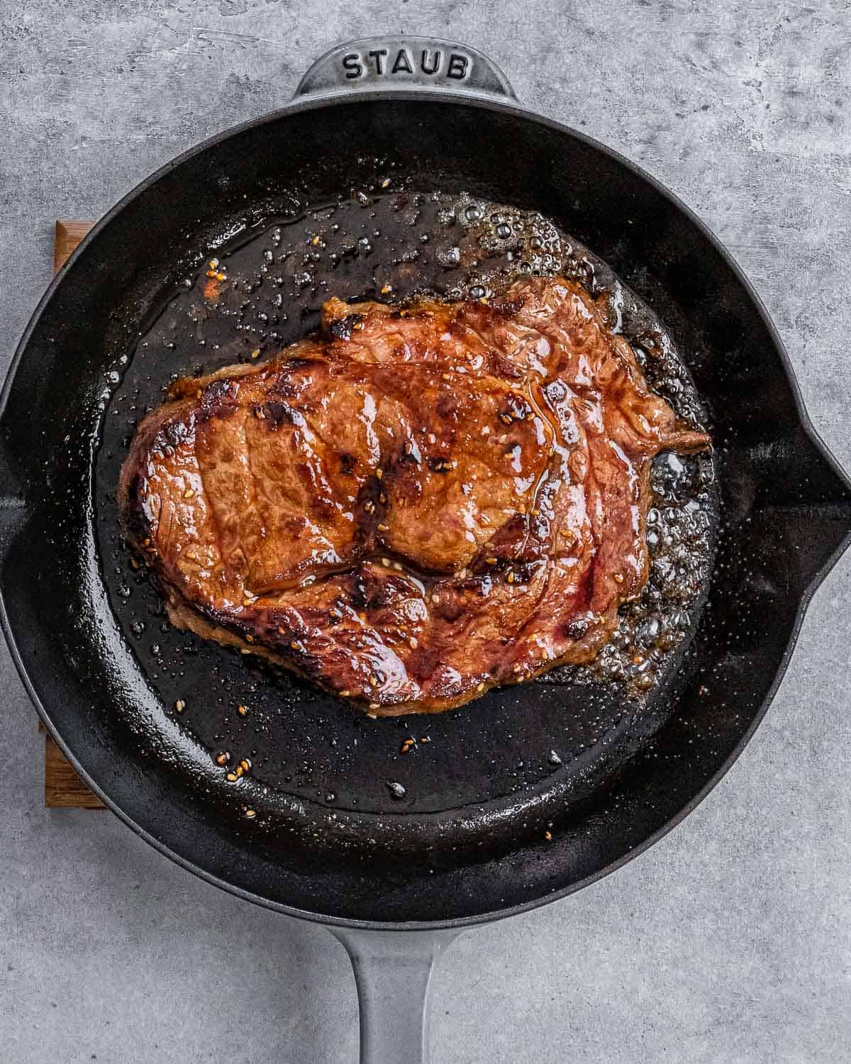 Cooking steak in a large skillet.