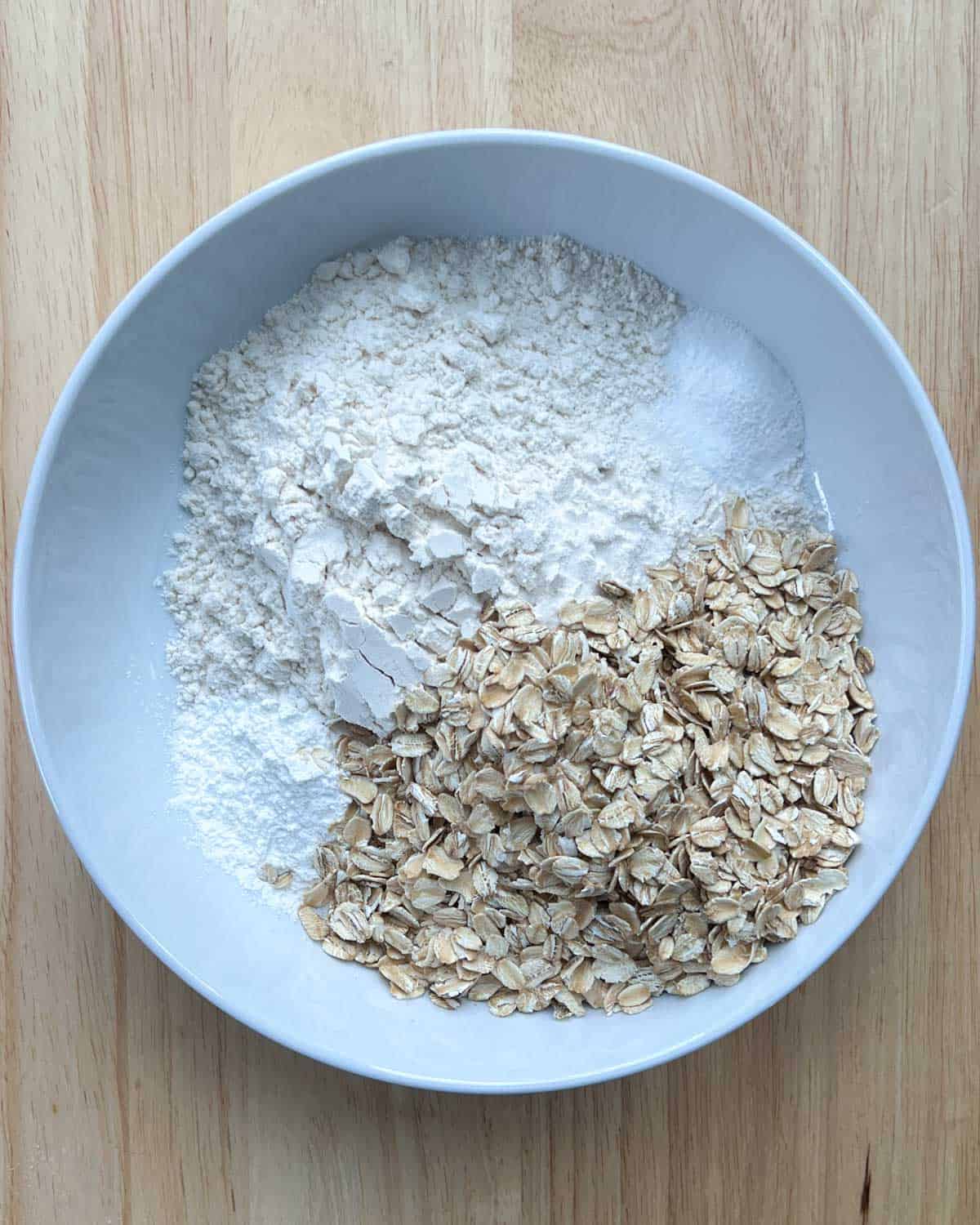 a round bowl with flour, oats, baking powder, and baking soda.