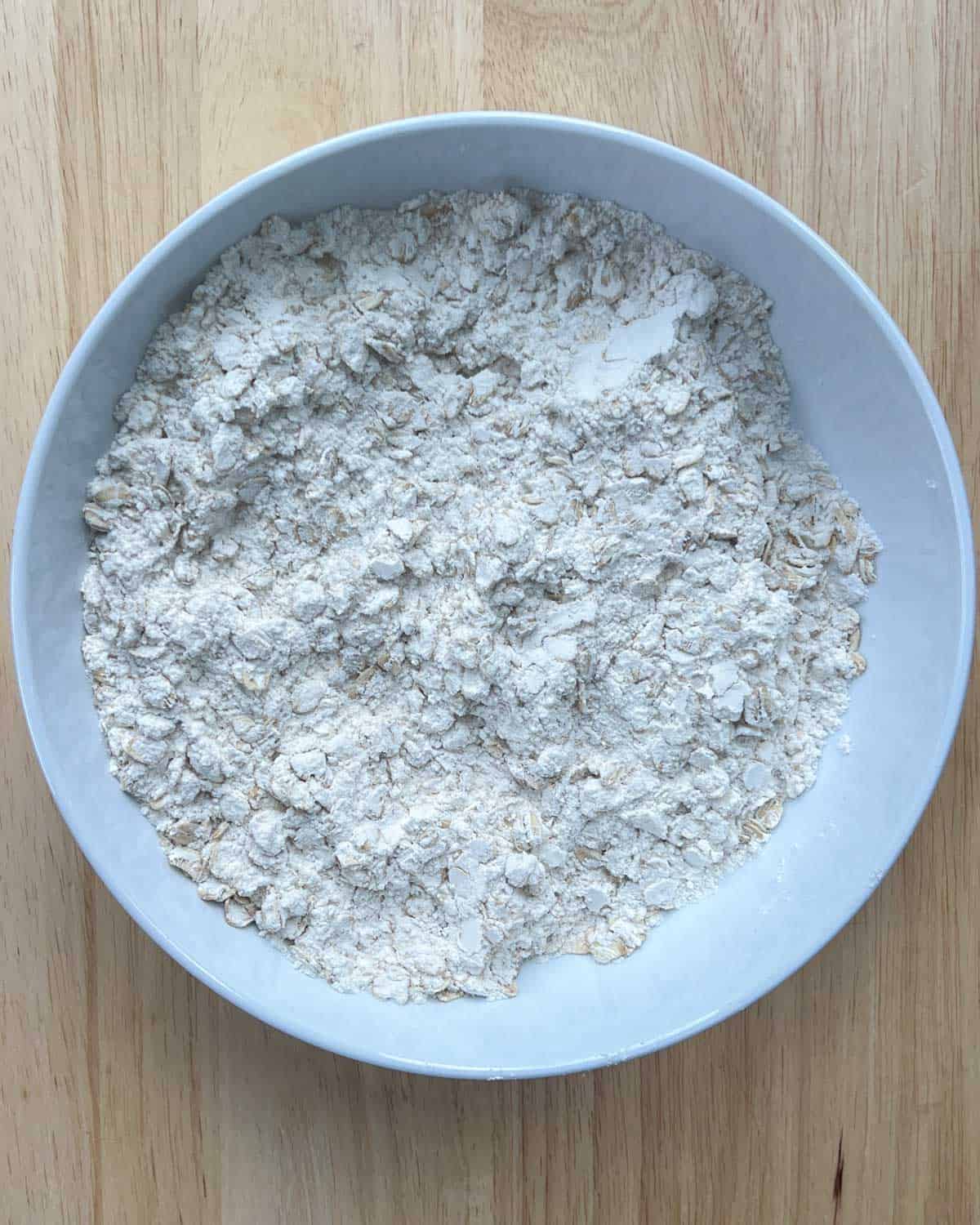 dry flour ingredients mixed in a round white bowl to make banana bread.