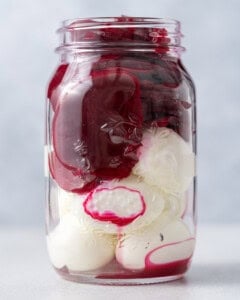 Glass mason jar packed tightly with pickled eggs and beets before all the liquid is added in.