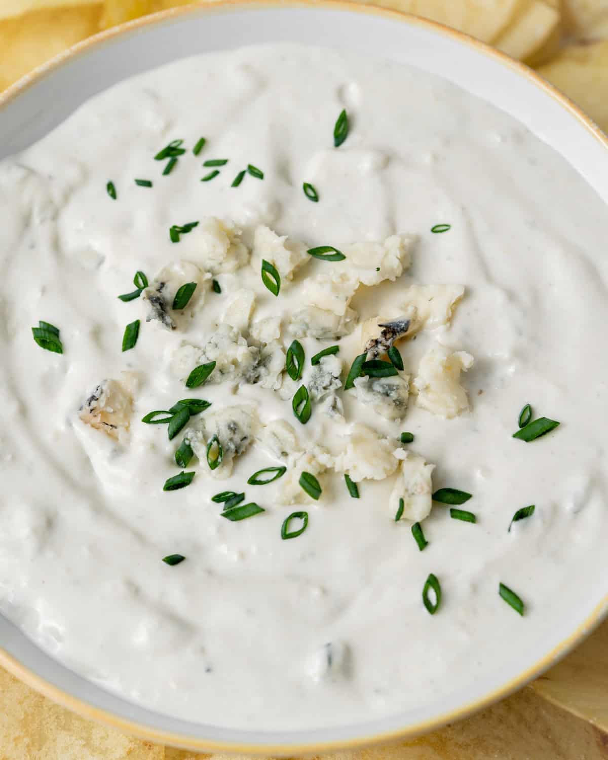 Blue cheese dip garnished with blue cheese crumbles and green onions.