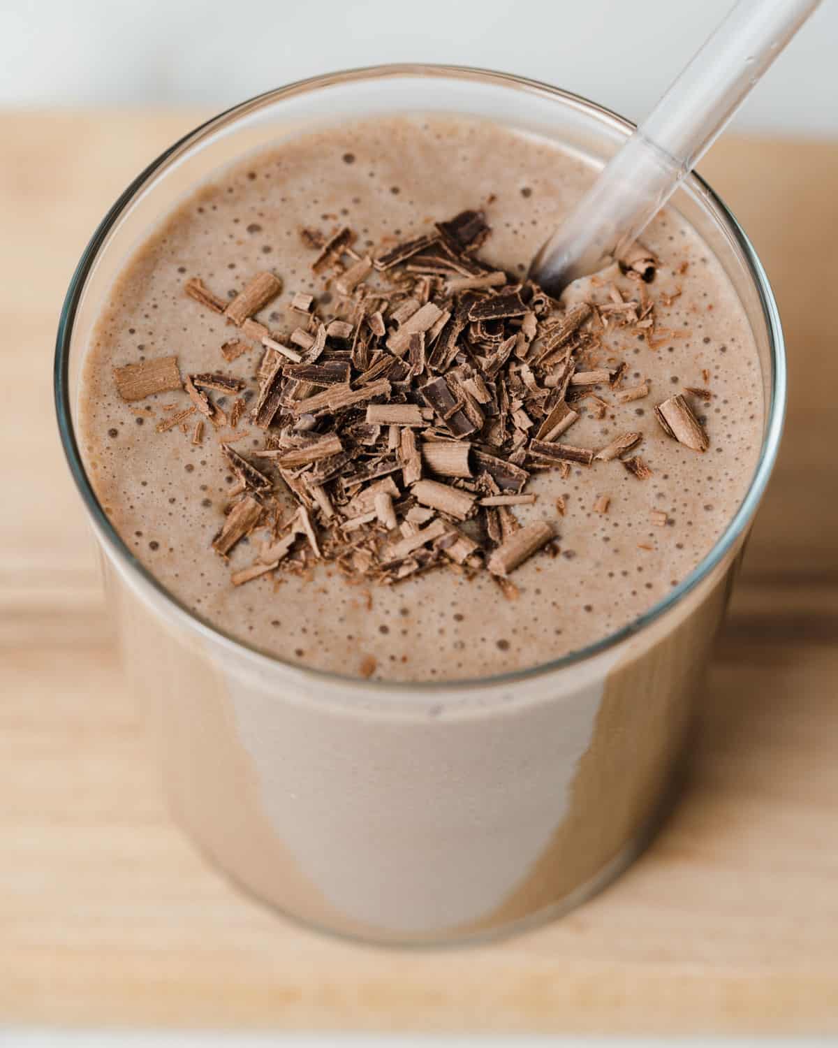 Coffee smoothie with a straw and topped with shaved chocolate.