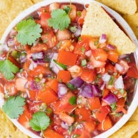 a round bowl with pico de galo salsa and tortilla chips around it.