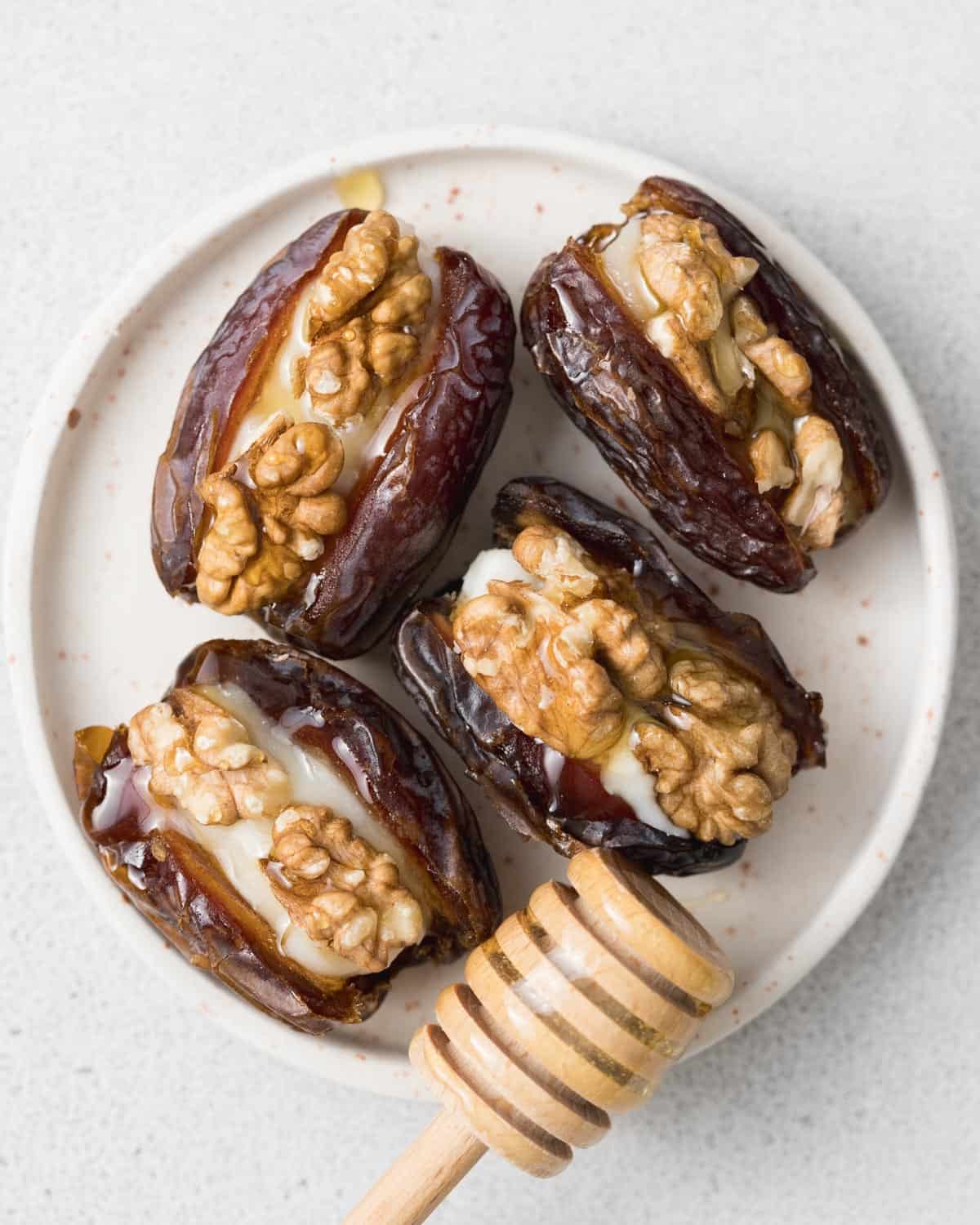 adding a drizzle of honey over stuffed dates served on a plate.