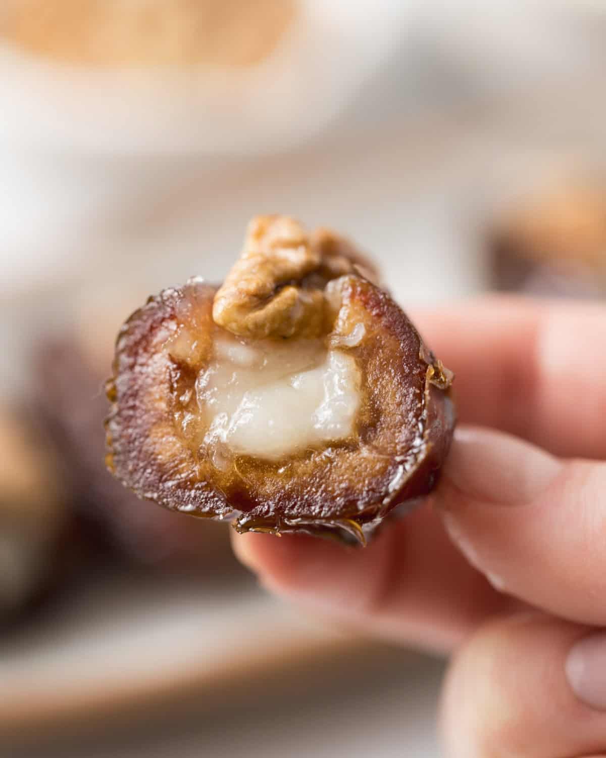 hand holding half a stuffed date with goat cheese and walnuts.