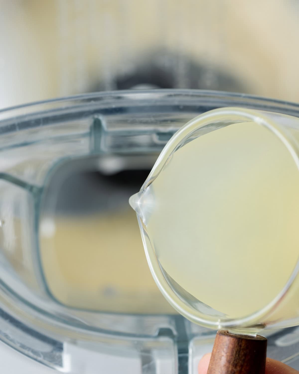 lemon juice being added into the food processor with blended garlic.