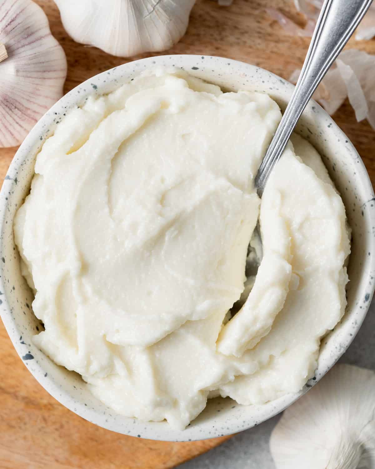 a spoon in a bowl with garlic sauce.