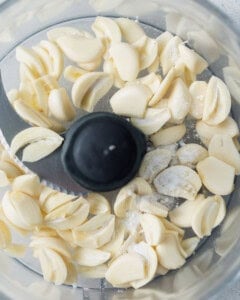 Sliced garlic placed in a food processor.