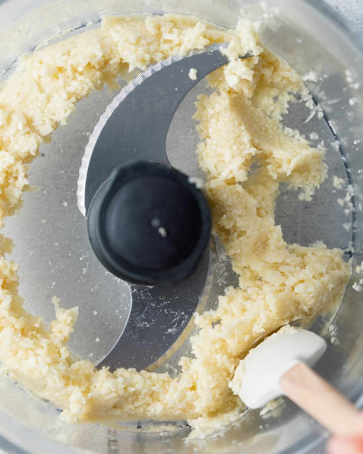 blended garlic in food processor with spatula scraping sides down.