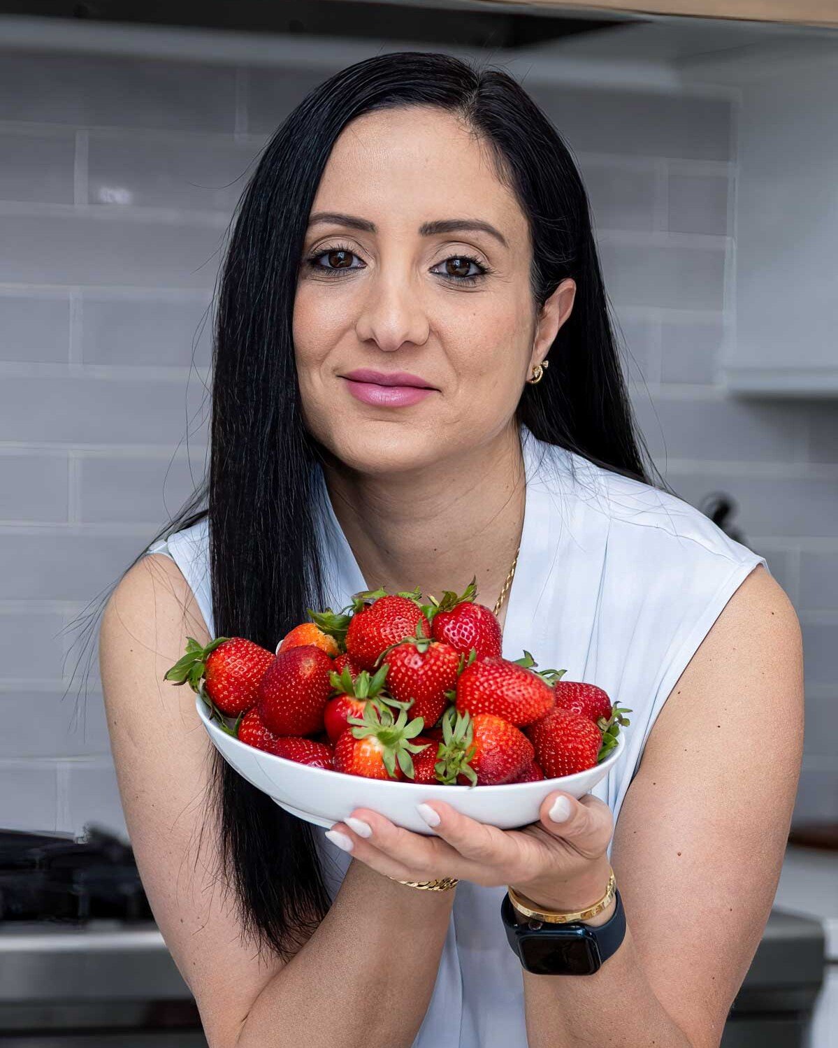 rena in a white shirt holding a bowl of strawberries