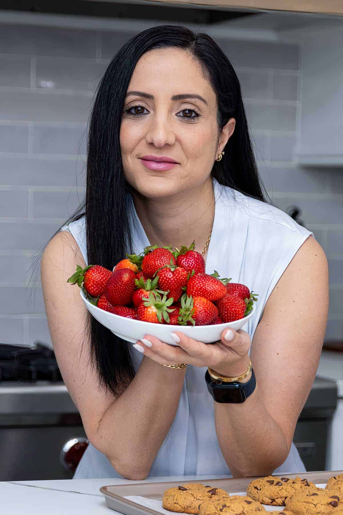 rena in a white shirt holding a bowl of strawberries