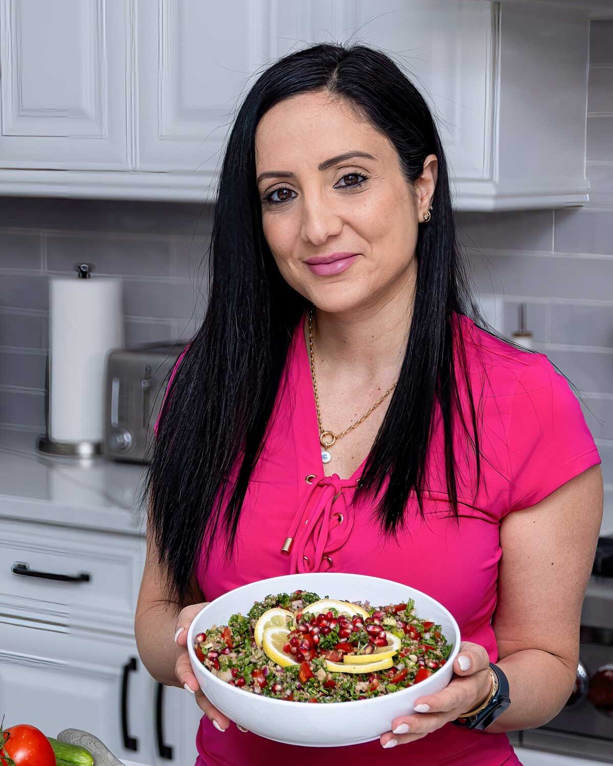 rena in a pink shirt holding a white bowl that has tabbouleh