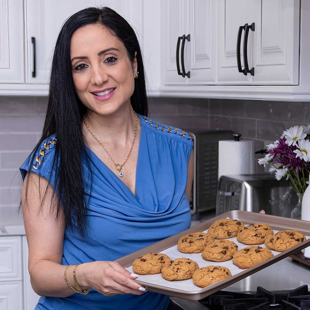 rena is holding a sheet pan with cookies.