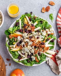 Bowl filled with greens, with pear, cheese and cranberries on top.