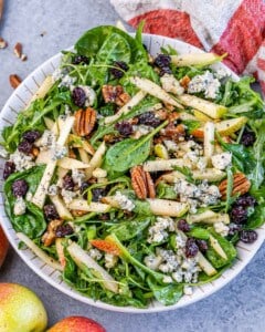 Close-up of the finished arugula pear salad showing texture of greens, pears, and crumbled cheese.
