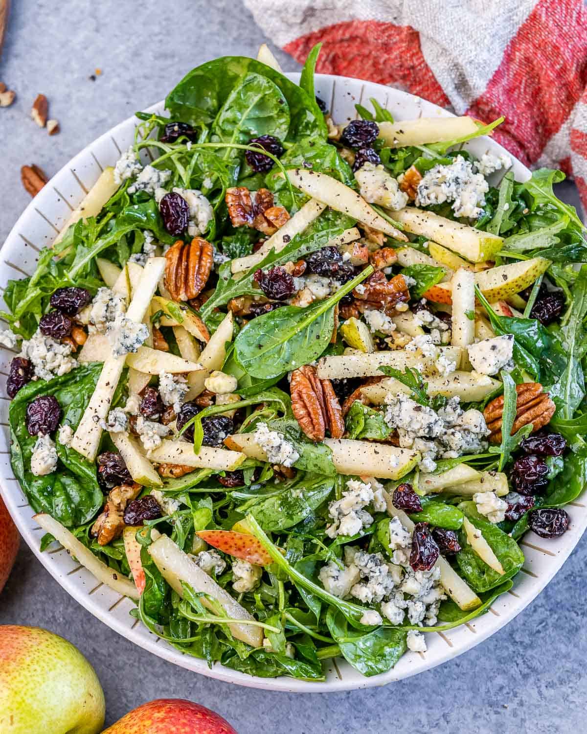 Close-up of the finished arugula pear salad showing texture of greens, pears, and crumbled cheese.