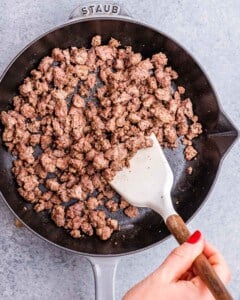 Mincing ground beef in a skillet.