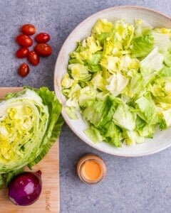 Chopped lettuce in a white bowl near a cutting board.