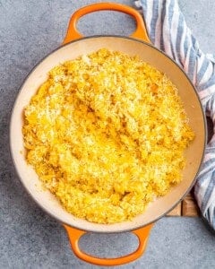 Rice cooking in turmeric broth, bubbling gently in a large pot.